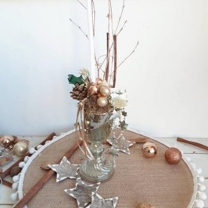 Ejemplo de arreglo navideño en copa de vidrio, con piñas, bolitas, cintas y velas.