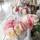 Ramilletes de rosas artificiales que parecen de verdad, en jarrones altos y estilizados de color blanco.