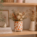 maceta decorativa ceramica estampado naranjas con flores secas del campo en una estantería de madera