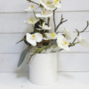 Orquídea artificial de flores blancas que parece de verdad en macera de cerámica también de color blanco.